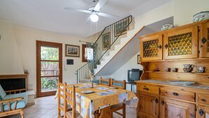 Un comedor con una mesa, sillas, una escalera, armarios de madera y un televisor.