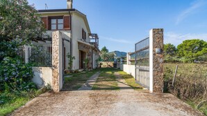 Una casa con entrada de piedra, un camino de entrada pavimentado y un jardín con plantas florecientes.