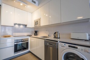 A modern kitchen with stainless steel appliances, a dishwasher, and a washing machine.