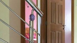 Een trap met een metalen leuning en een deur die leidt naar een kamer met roze muren.