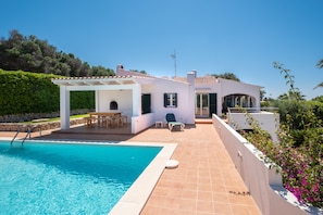 En villa ved poolen med swimmingpool, udendørs møbler og have.