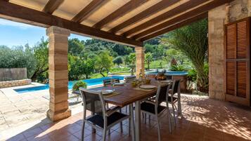 An outdoor patio with a pool, dining table, and chairs.