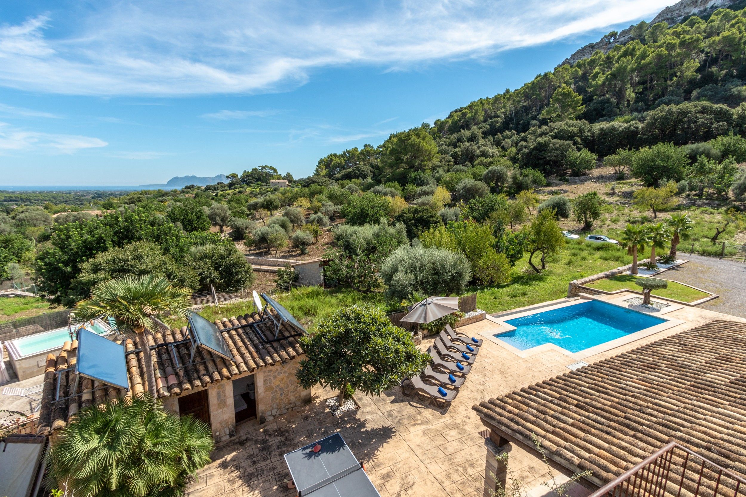 A villa with a swimming pool, outdoor seating, and a view of the surrounding landscape.