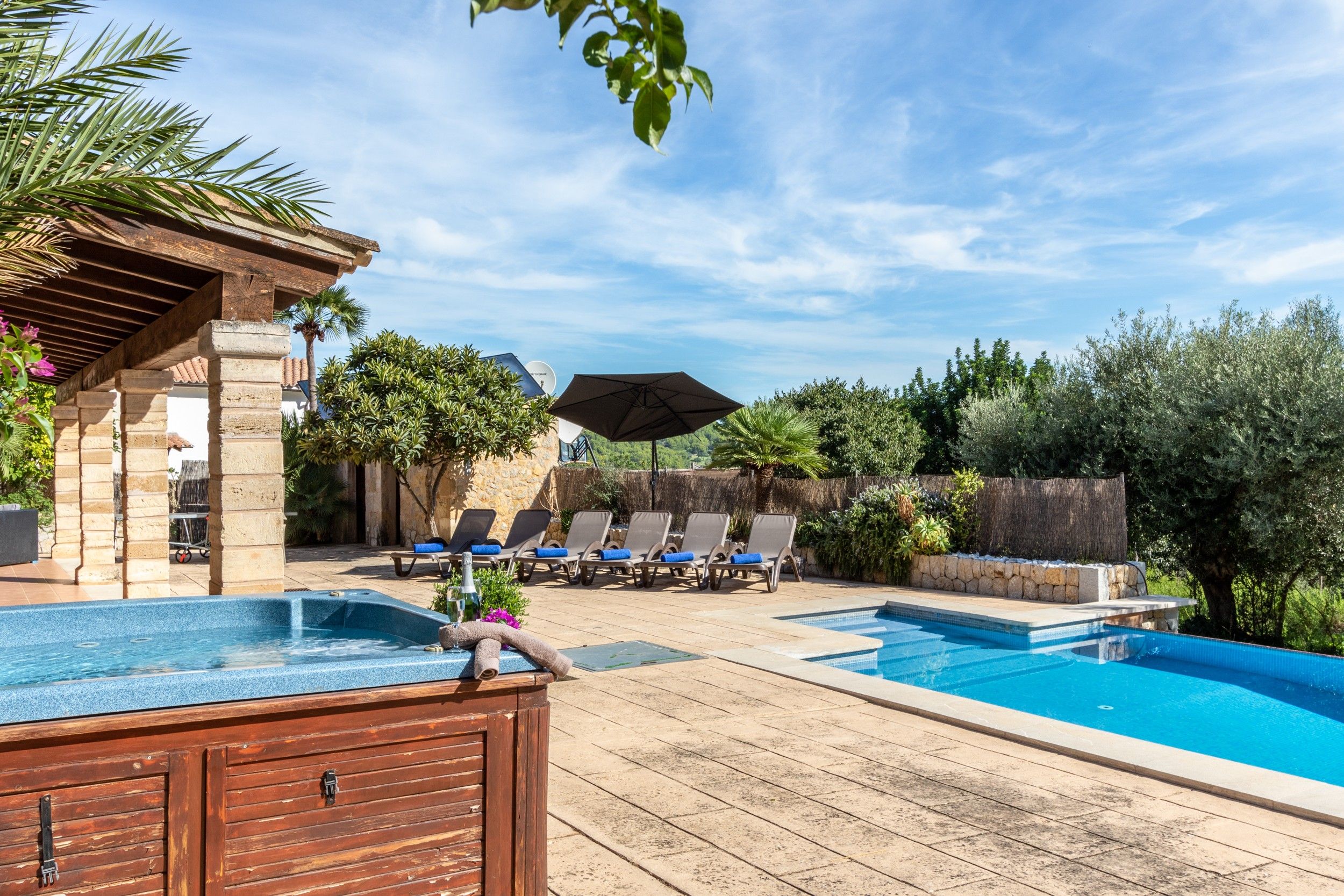 A pool area with lounge chairs, a hot tub, and a pergola.