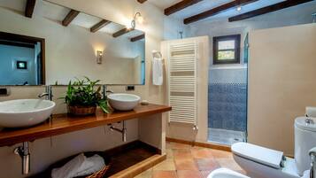 A bathroom with two sinks, a mirror, a towel rack, a shower, and a toilet.