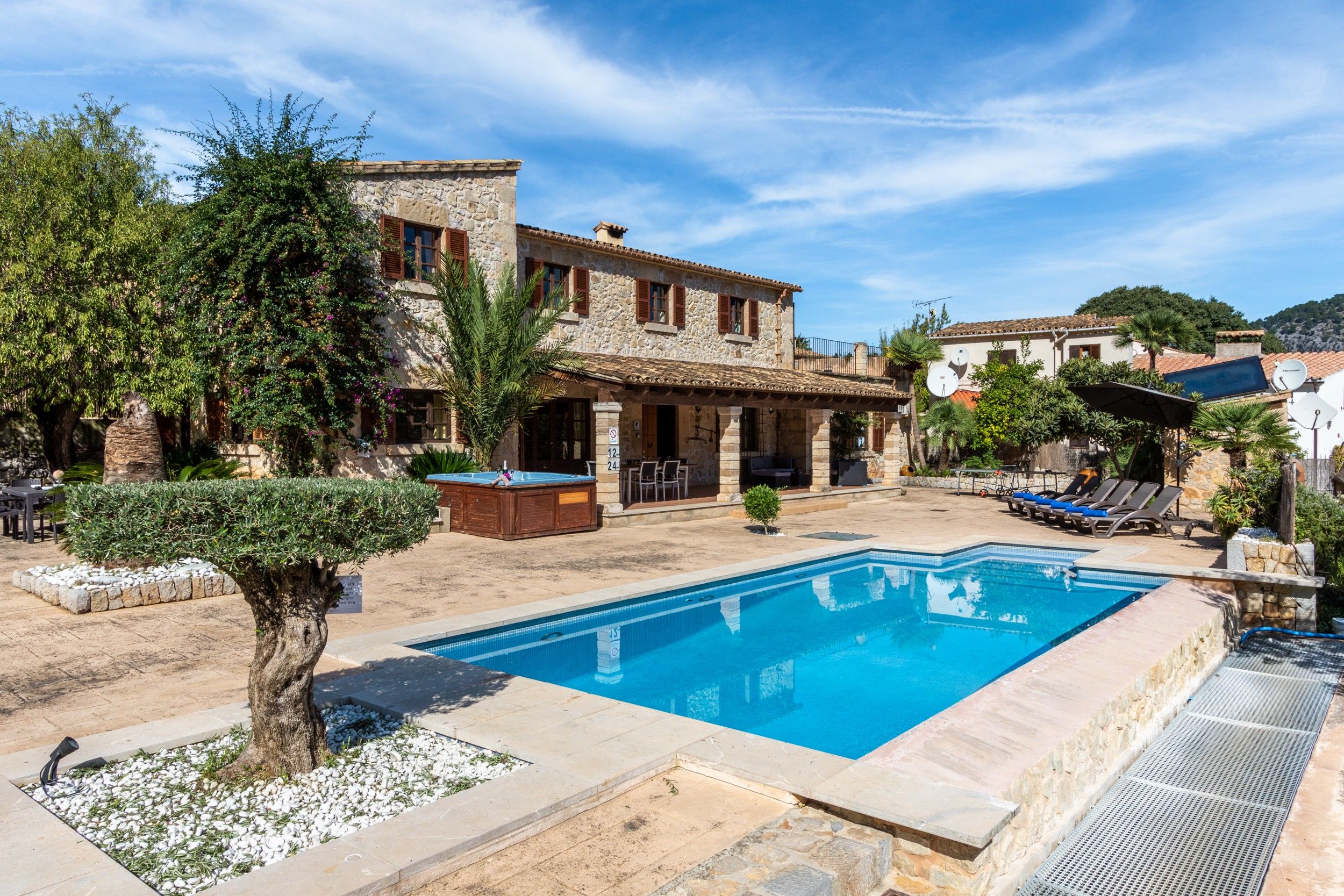 A poolside area with a stone building, outdoor seating, and a clear blue pool.