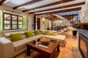 A spacious living room with a sectional sofa, a wooden coffee table, and a stone fireplace.