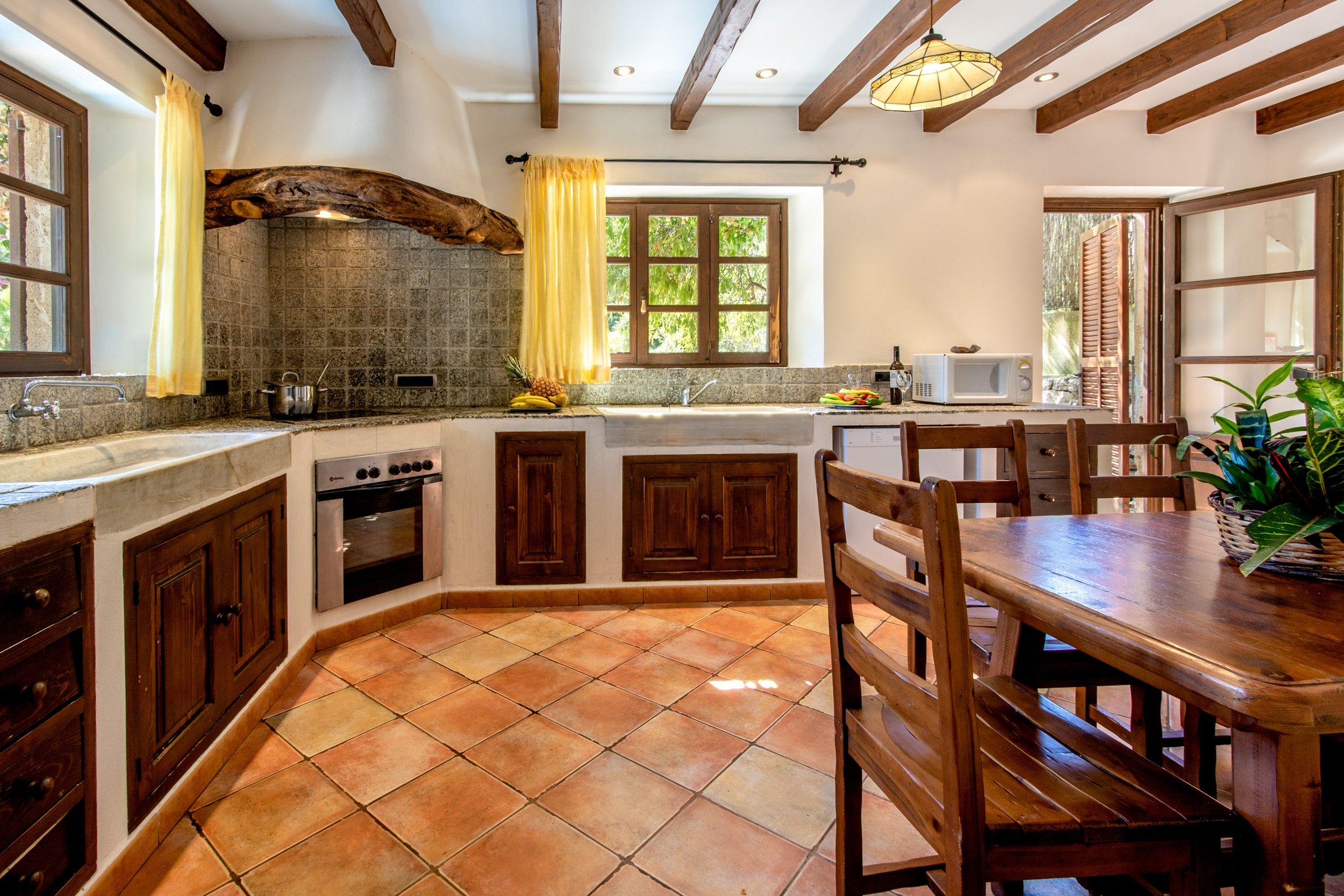 A kitchen with a stone backsplash, wooden cabinets, a built-in oven, and a dining area with a wooden table and chairs.