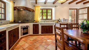 A kitchen with a stone backsplash, wooden cabinets, a built-in oven, and a dining area with a wooden table and chairs.