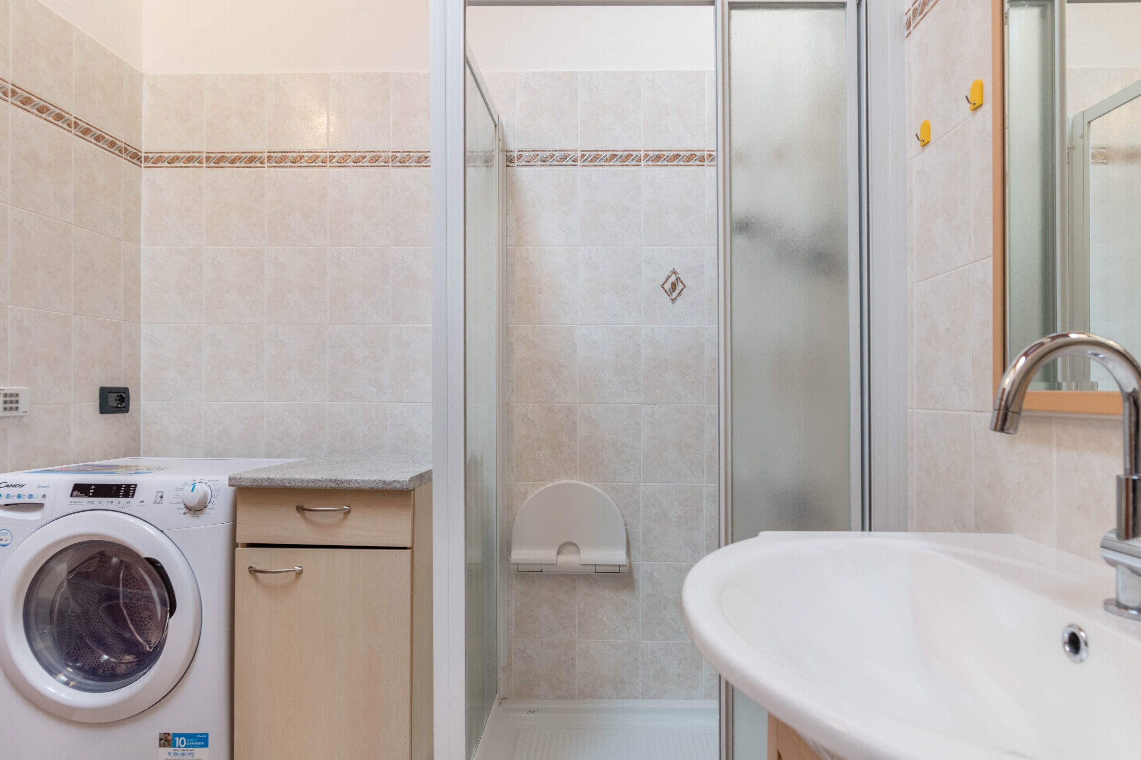 Een moderne badkamer met een wasmachine, een douchecabine van glas en een wastafel.