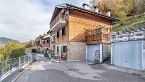 A multi-story wooden house with a balcony, stone facade, and a garage. - Apartment 'Dimora La Quiete' with Mountain View, Private Terrace and Balcony (Bedollo)