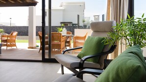 Una sala moderna con sofá, sillones y vista al patio exterior.