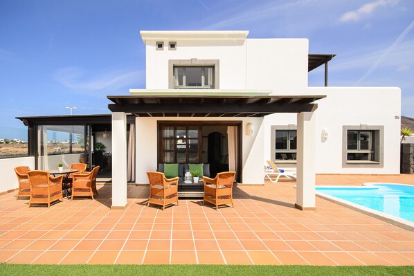 A modern house with a patio, outdoor seating, and a swimming pool.