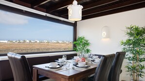 Un comedor con una mesa dispuesta para cuatro personas, vistas al paisaje y dos plantas en macetas.