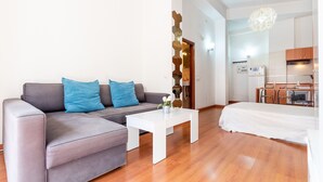 Ein modernes Wohnzimmer mit einem grauen Sofa, einem weißen Couchtisch und einem Bett mit weißer Bettdecke.