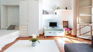 Ein Schlafzimmer mit einem Bett, einem Schreibtisch mit Computer, einem Stuhl und einem Bücherregal.