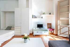 A bedroom with a bed, a desk with a computer, a chair, and a bookshelf.