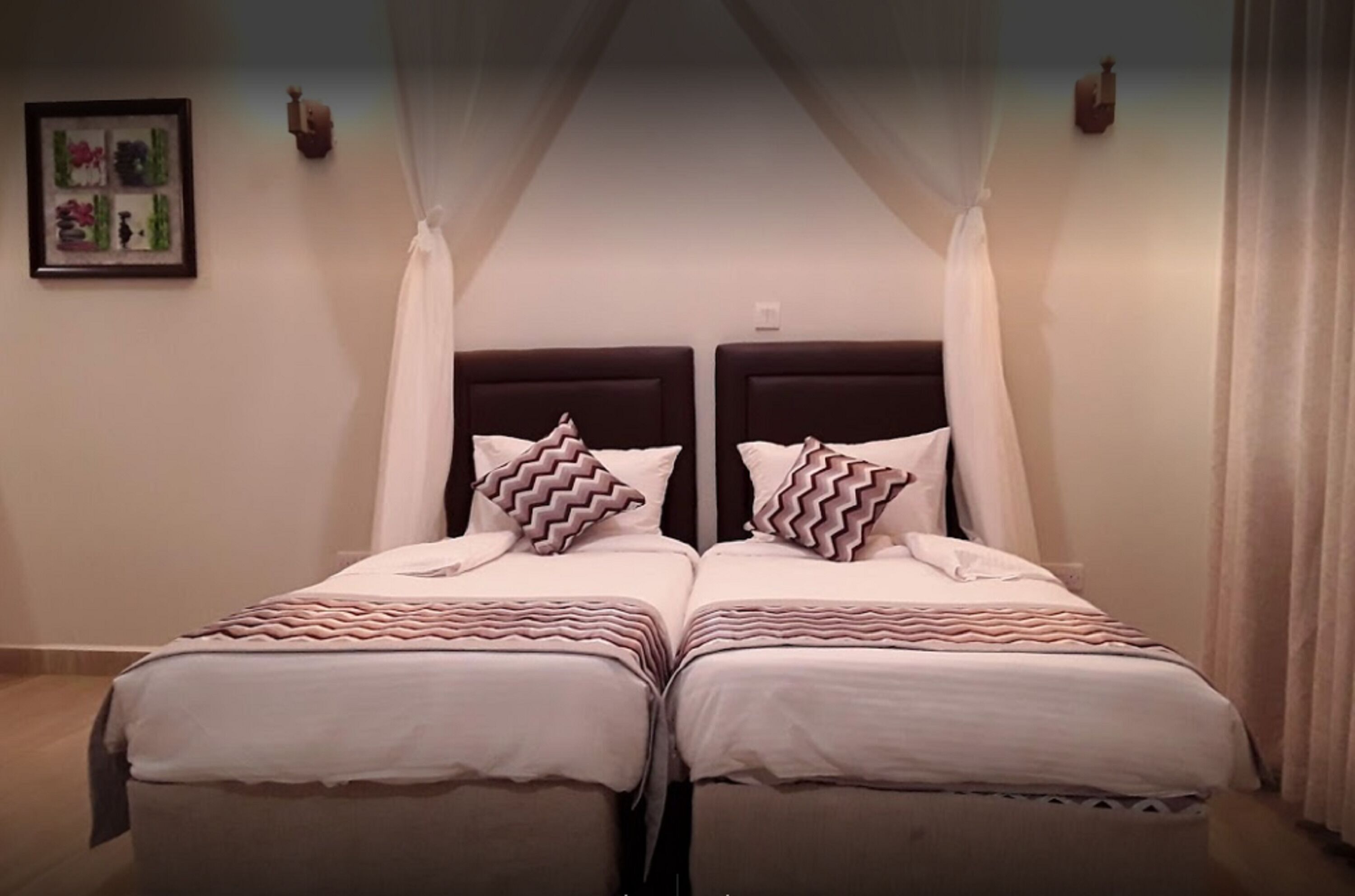 A double bed with a canopy, two bedside tables, and a framed picture on the wall.