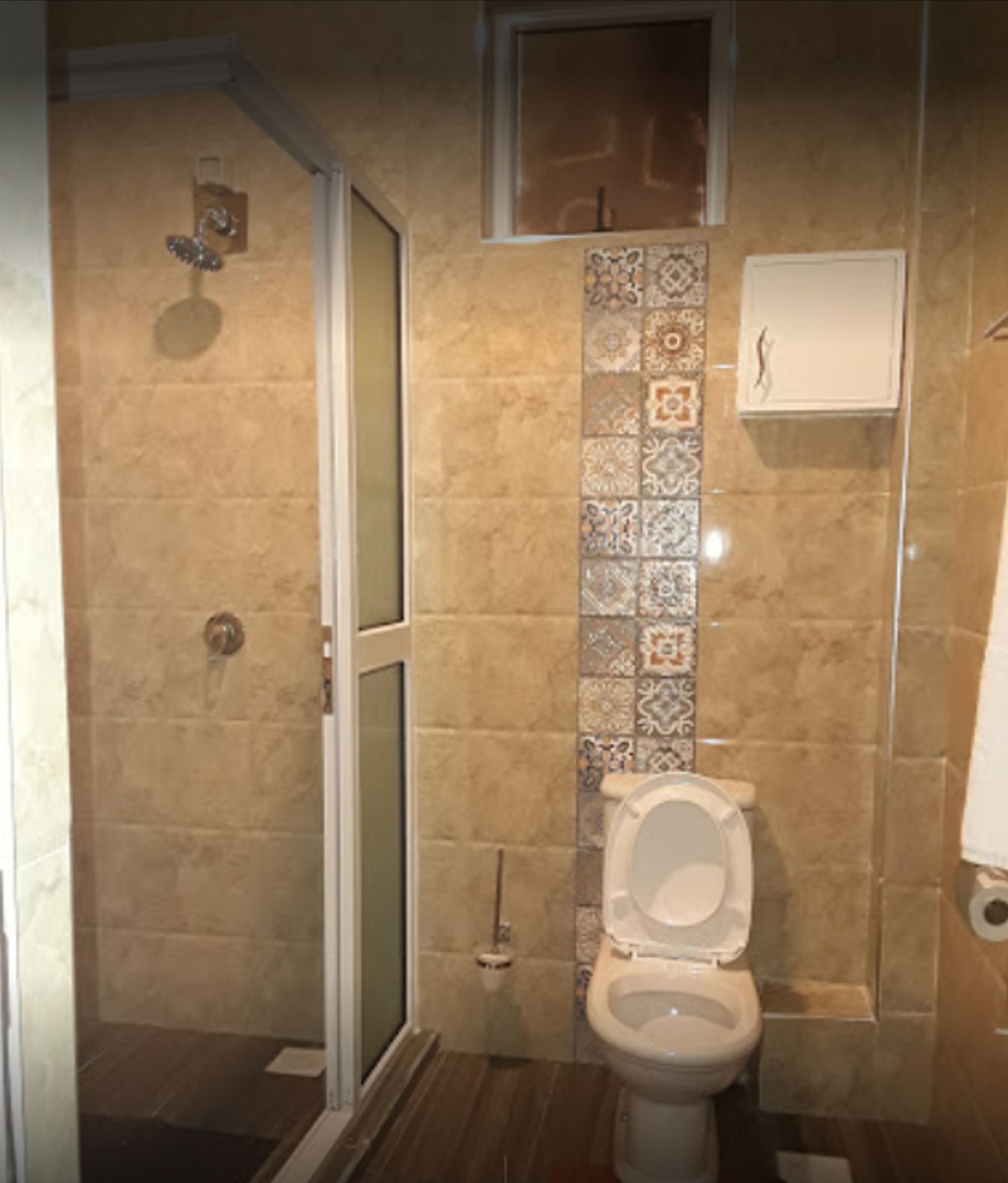 Ein Badezimmer mit Dusche, Toilette und gefliesten Wänden.