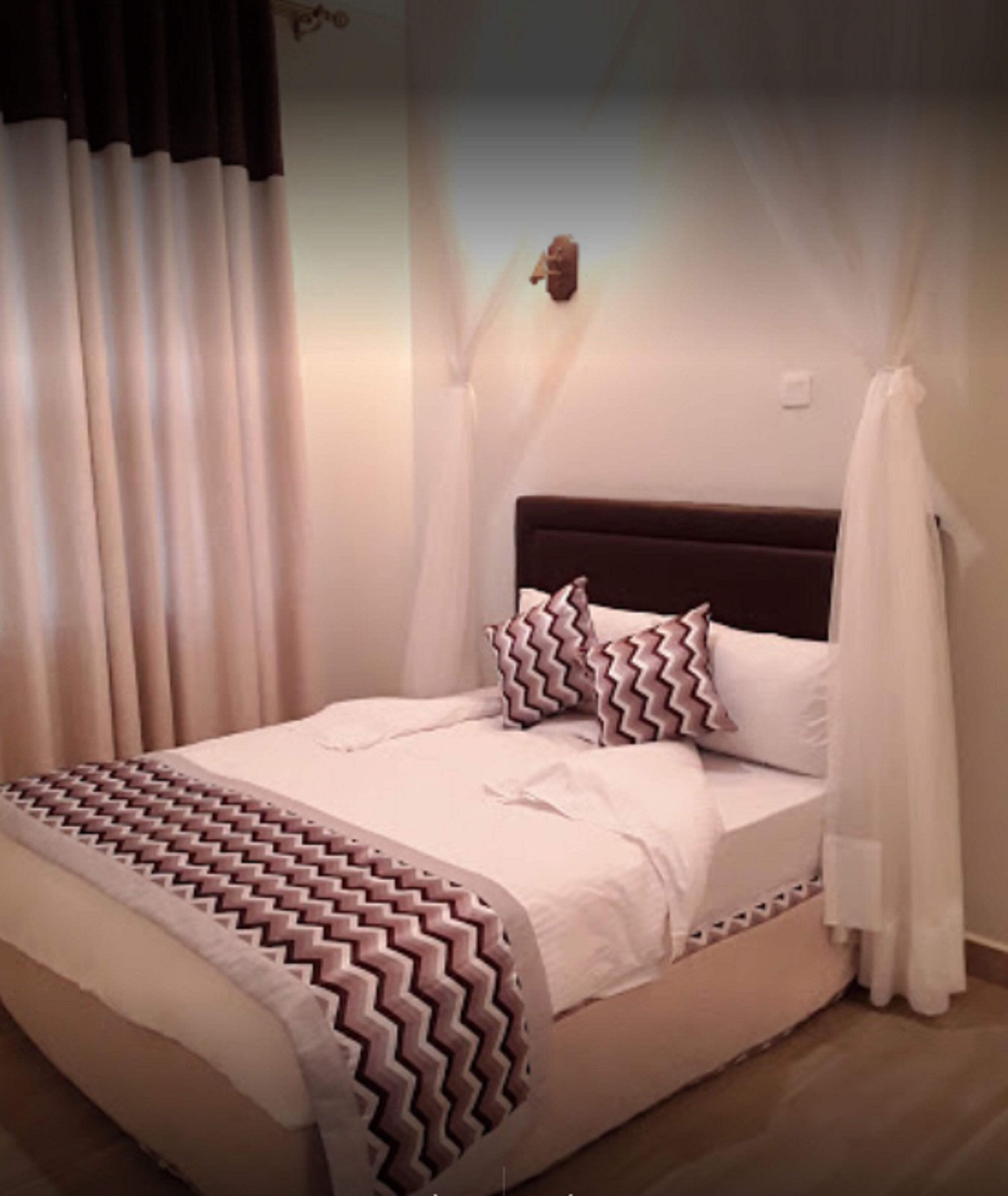 A bed with a patterned bedspread, a headboard, and a canopy.