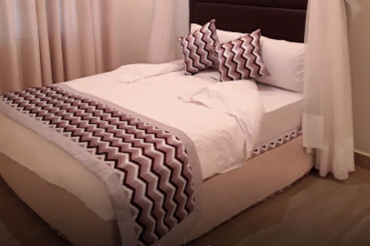 Ein Bett mit einem gemusterten Überwurf, einem Kopfteil und einem Baldachin.