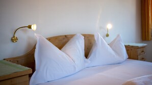 Ein ordentlich bezogenes Bett mit weißen Kissen und einem hölzernen Kopfteil, zwei Nachttische mit Lampen sowie ein weiterer Nachttisch mit einer Lampe.