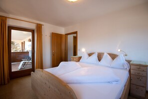 A bedroom with a wooden bed, a nightstand, a mirror, and a sliding door leading to an outdoor area.