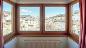 A room with a large window overlooking a town with buildings and mountains.