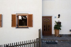 Un edificio con puerta de madera, ventana con persianas y un pequeño porche.