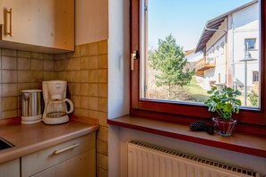 Una cocina con vista al exterior, un radiador y una planta en el alféizar.