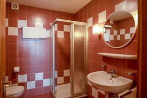 Une salle de bain équipée d’une douche, de toilettes, d’un lavabo et d’un miroir.