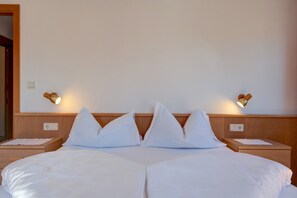 A hotel room with a large bed, two bedside tables, and wall-mounted lamps.