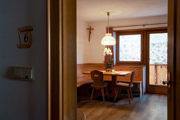 Un espace repas avec des meubles en bois, un luminaire suspendu et une fenêtre donnant sur un beau paysage.