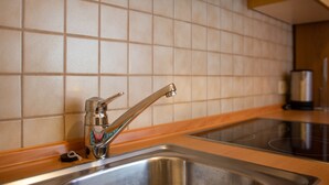 A kitchen with a stainless steel sink, a modern faucet, and a tiled backsplash. - Comfortable Apartment 3 "Zur Sonne" with Mountain View, Garden & Wi-Fi (Lajen)