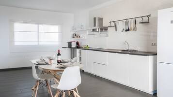 A modern kitchen with white cabinetry, a dining area with a table and chairs, and a window providing natural light.