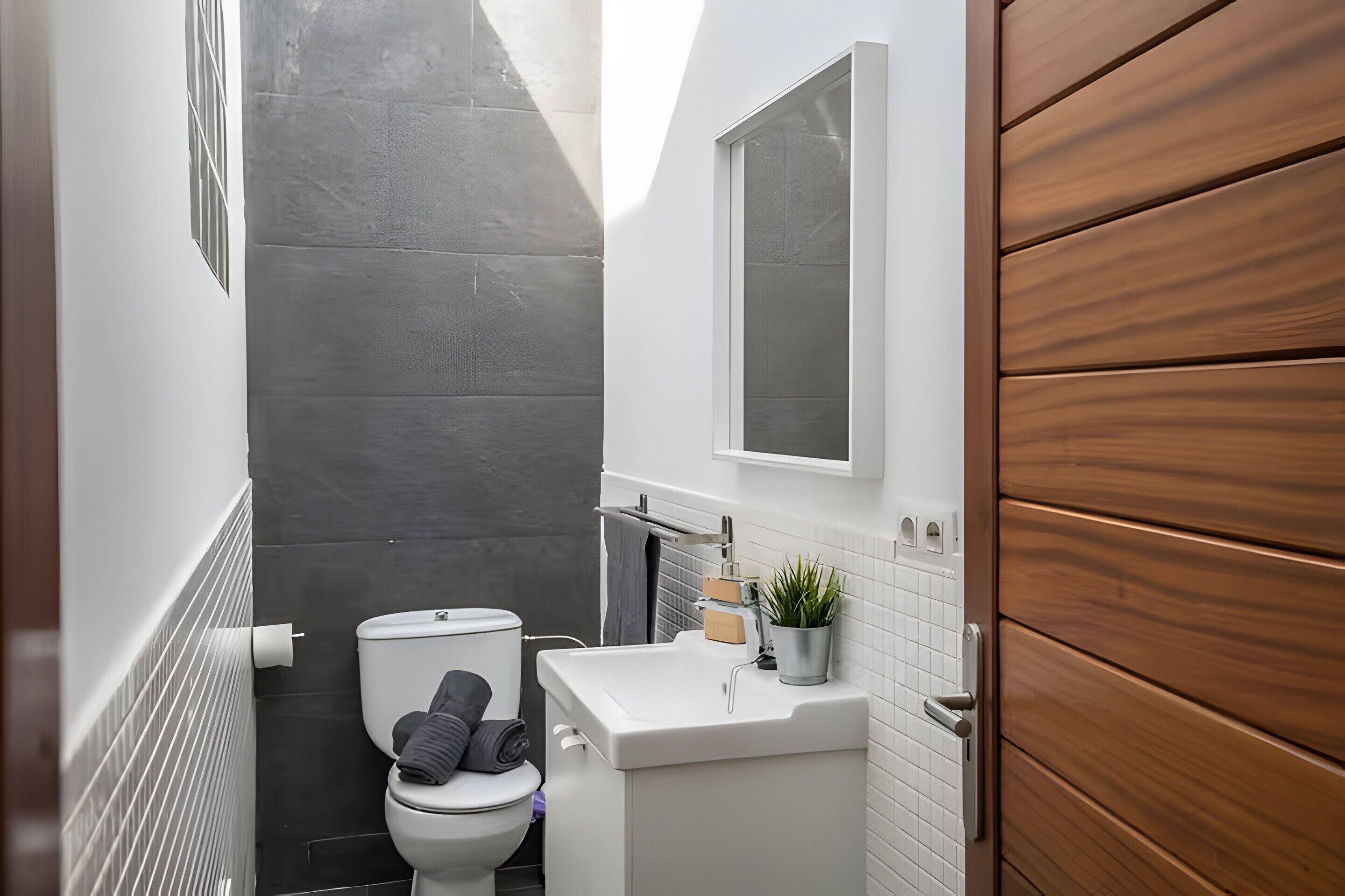 A modern bathroom with a toilet, sink, and a potted plant.