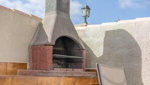 A stone structure with a chimney, a metal grill, and a street lamp in the background. - Rural Home "La Ermita" with Pool, Terrace, Wi-Fi & Air Conditioning (Conil de la Frontera)