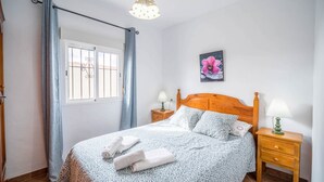A bedroom with a bed, curtains, a nightstand, a lamp, a picture on the wall, and a window. - Rural Home "La Ermita" with Pool, Terrace, Wi-Fi & Air Conditioning (Conil de la Frontera)