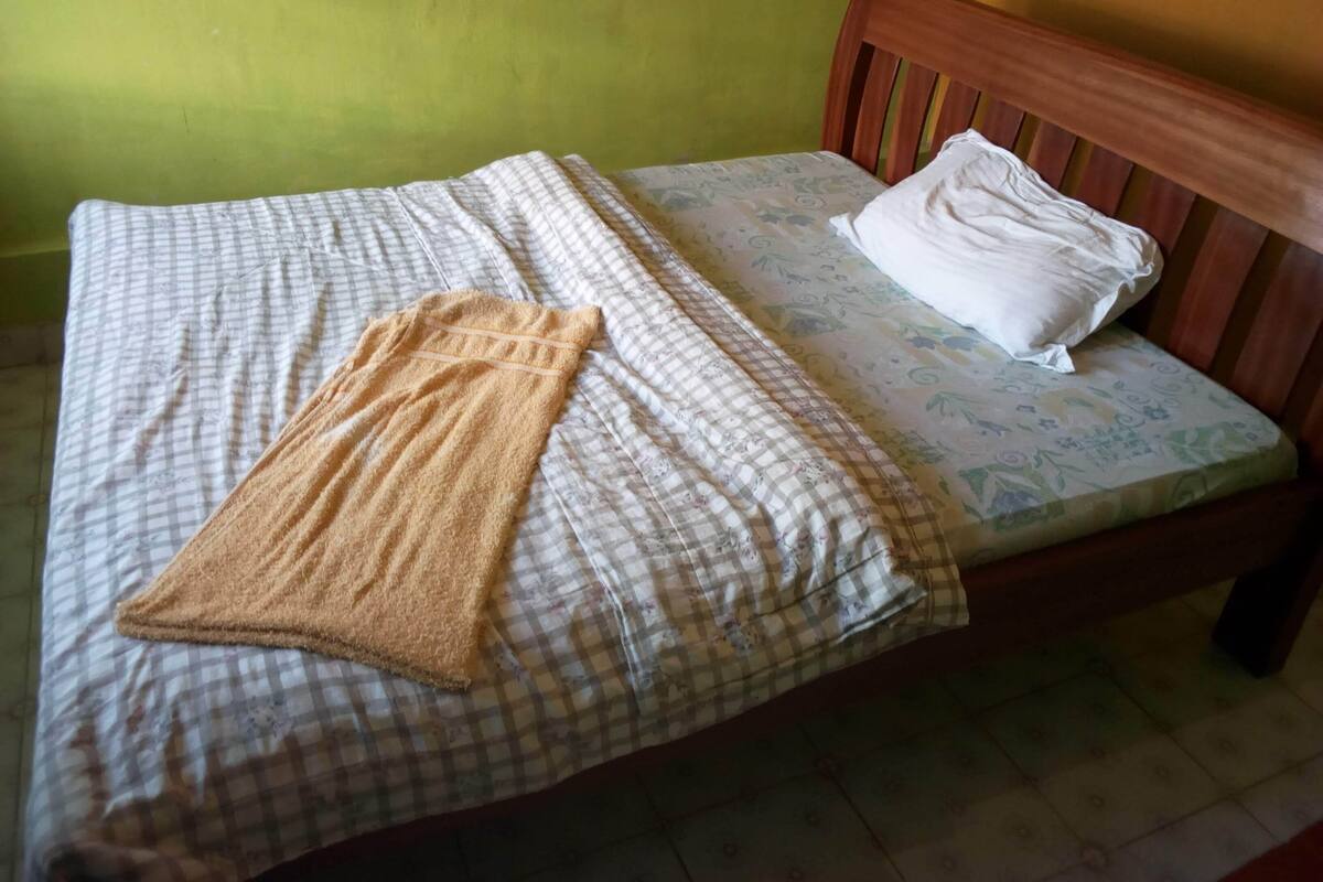 A bed with a checkered bedspread, a brown towel, and a white pillow.