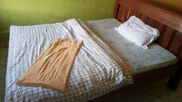 A bed with a checkered bedspread, a brown towel, and a white pillow.
