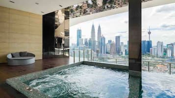 Une piscine intérieure moderne offrant une vue sur le paysage urbain, notamment sur les tours Petronas.