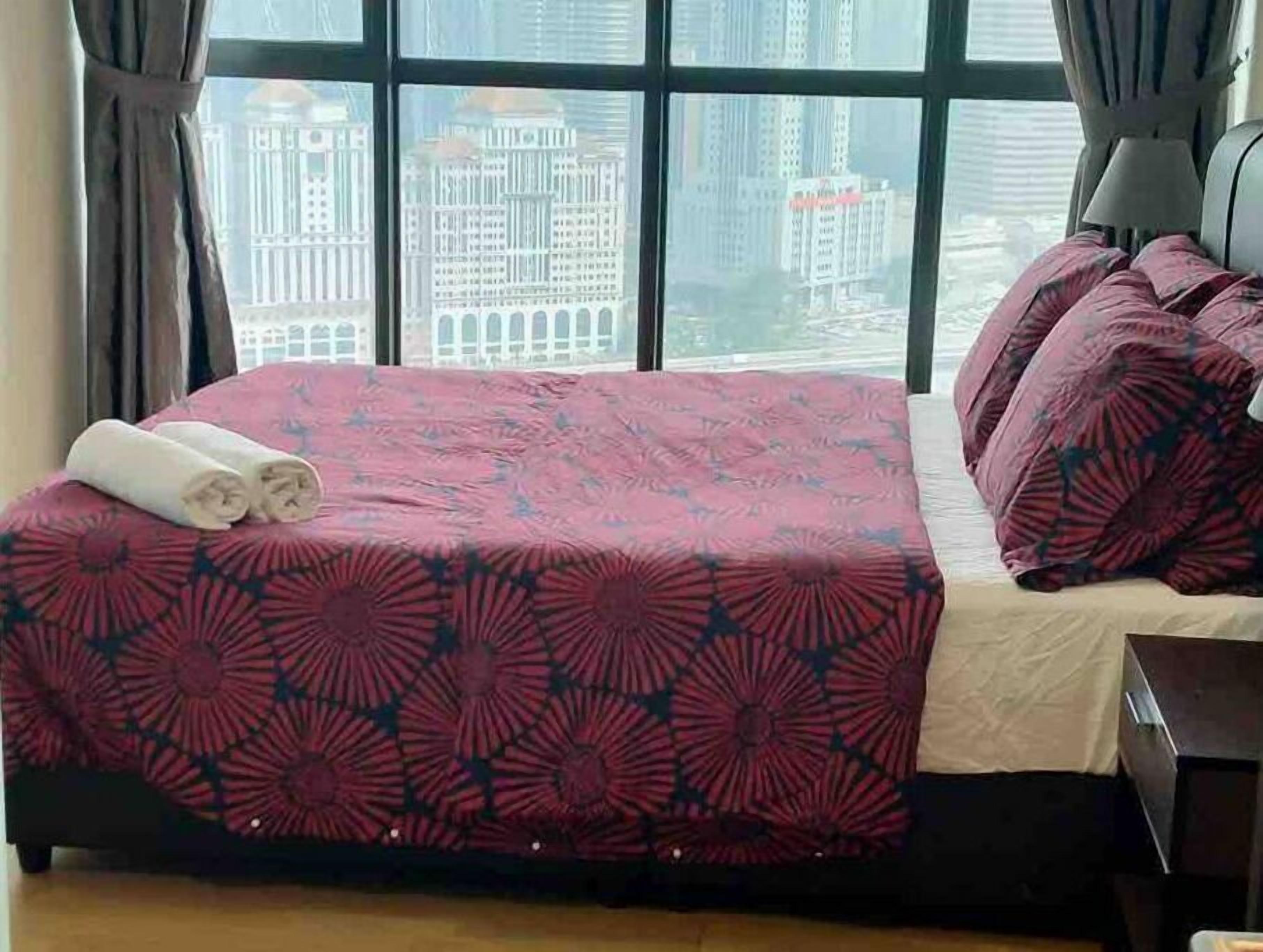 Une chambre d’hôtel avec un lit, une fenêtre donnant sur la ville et une table de chevet.