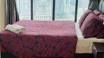 Une chambre d’hôtel avec un lit, une fenêtre donnant sur la ville et une table de chevet.