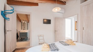 Et hotelværelse med seng, fjernsyn, badeværelse og træloft.
