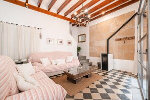 Un salon avec un sol à carreaux, un canapé, une table basse et une cheminée.
