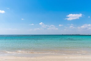 Ein Strand mit klarem türkisblauem Wasser und einem sandigen Ufer.