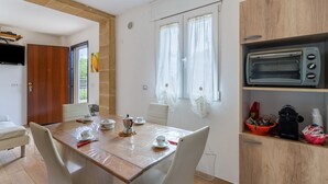 Un'area pranzo con un tavolo di legno, sedie, una macchina da caffè, tazze e un tostapane.
