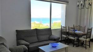 A living room with a sofa, a table, and a dining area with chairs.