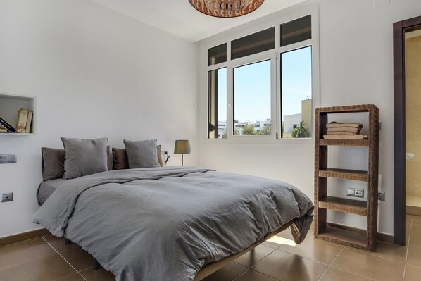 Ein Schlafzimmer mit Bett, Fenster, Ablagefläche und Lampe.