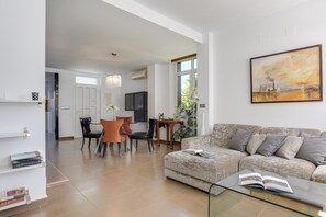 Ein modernes Wohnzimmer mit einer Couch, einem Glastisch und einem Essbereich mit Stühlen und Tisch.